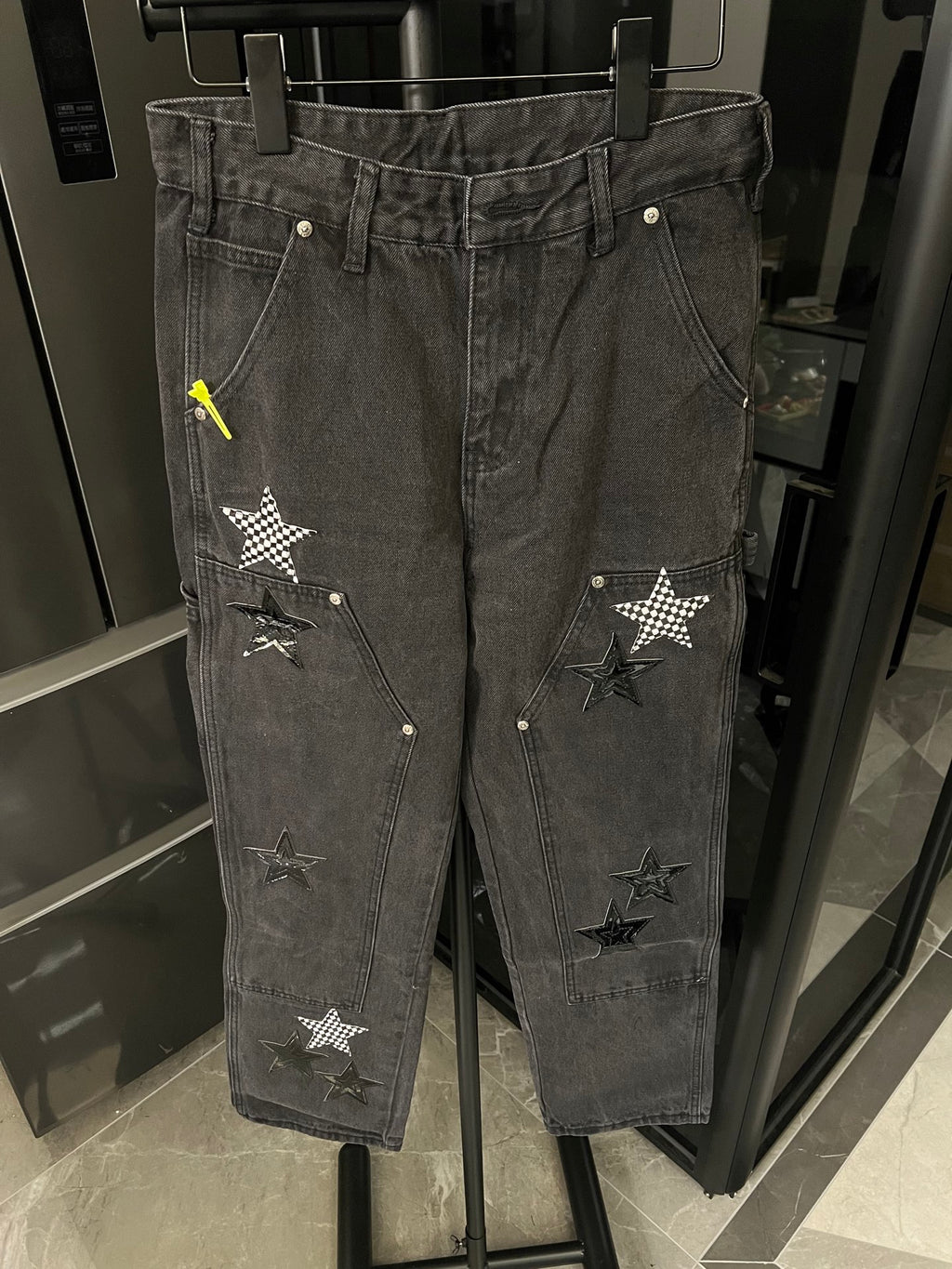 Dark gray denim pants with double-stitched waistband and star patches on front