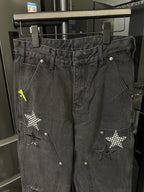 Dark gray denim pants with stitched star patches and metal buttons at pockets