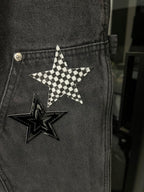 Dark gray denim pants pocket with checkered star patch and metal button