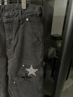 Dark gray denim pants close-up with star patch on front pocket area