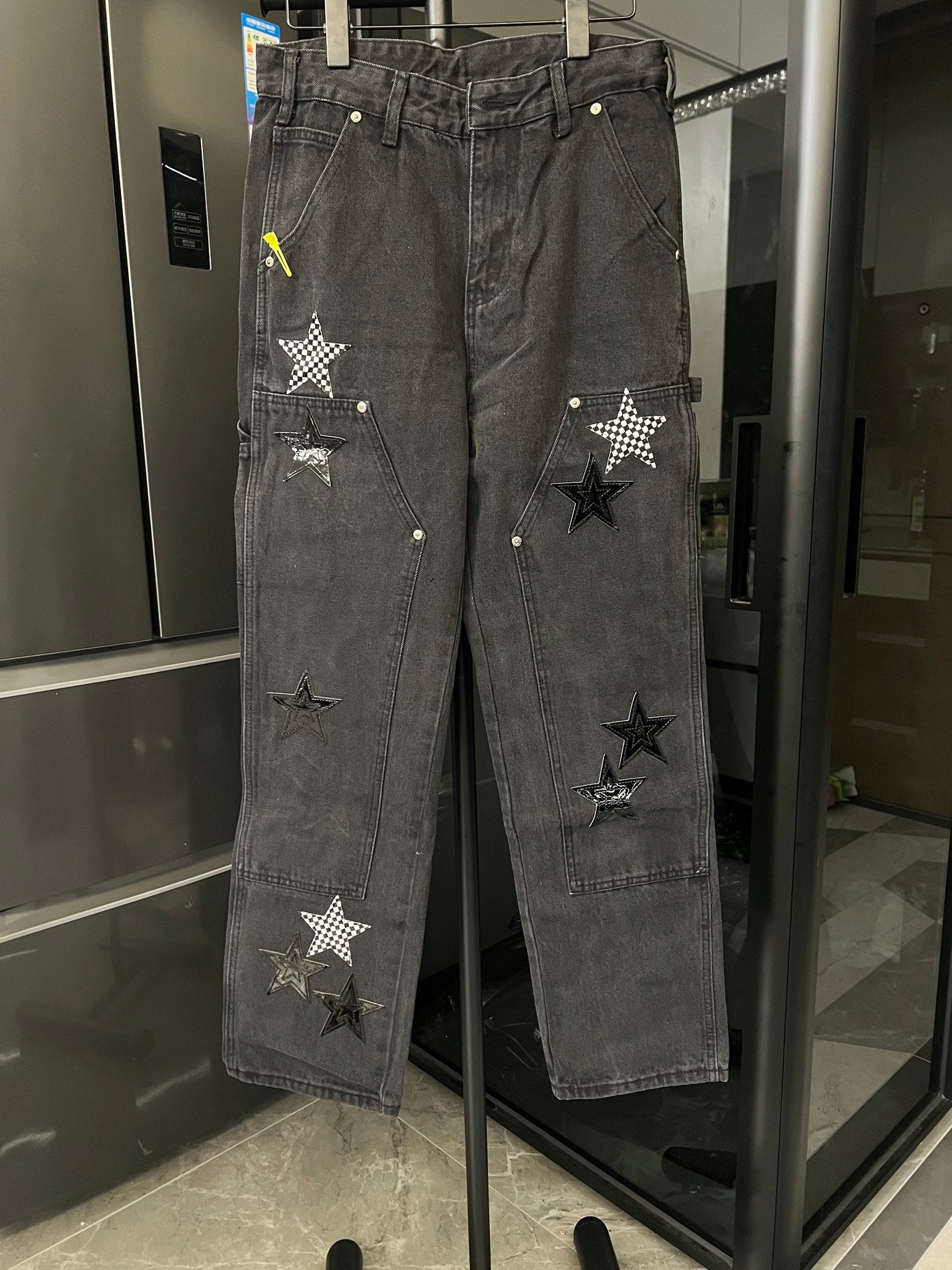 Dark gray denim pants with distressed finish and stitched star patches on legs