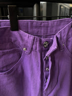 Purple pants waistband close-up with button placket and embroidered emblem