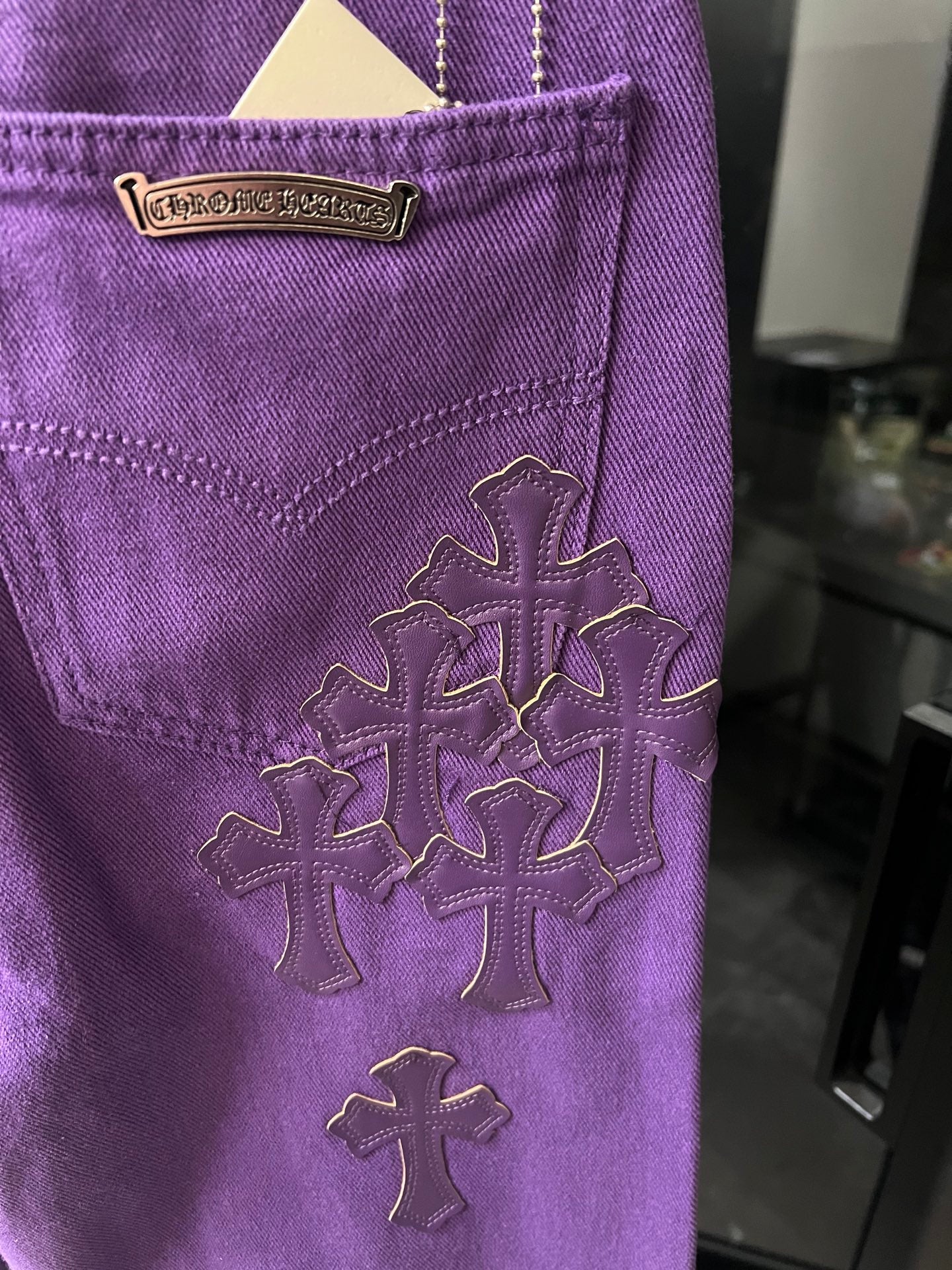 Purple pants with embroidered cross patches on pocket and side seam
