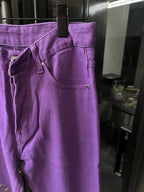 Purple pants close-up with front pocket and embroidered cross accent on leg