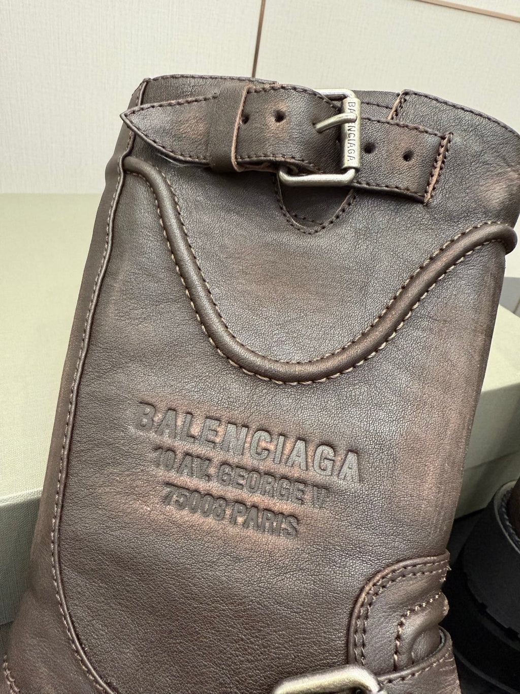 Balenciaga women’s leather boot with embossed logo, buckle strap, and stitched edges