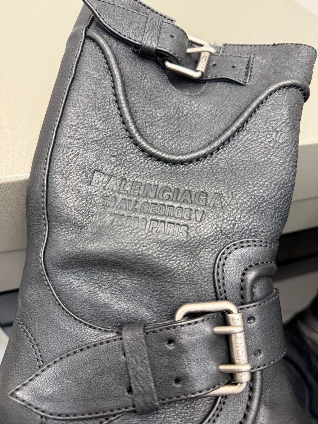 Gray leather boot with embossed logo and metal buckle strap
