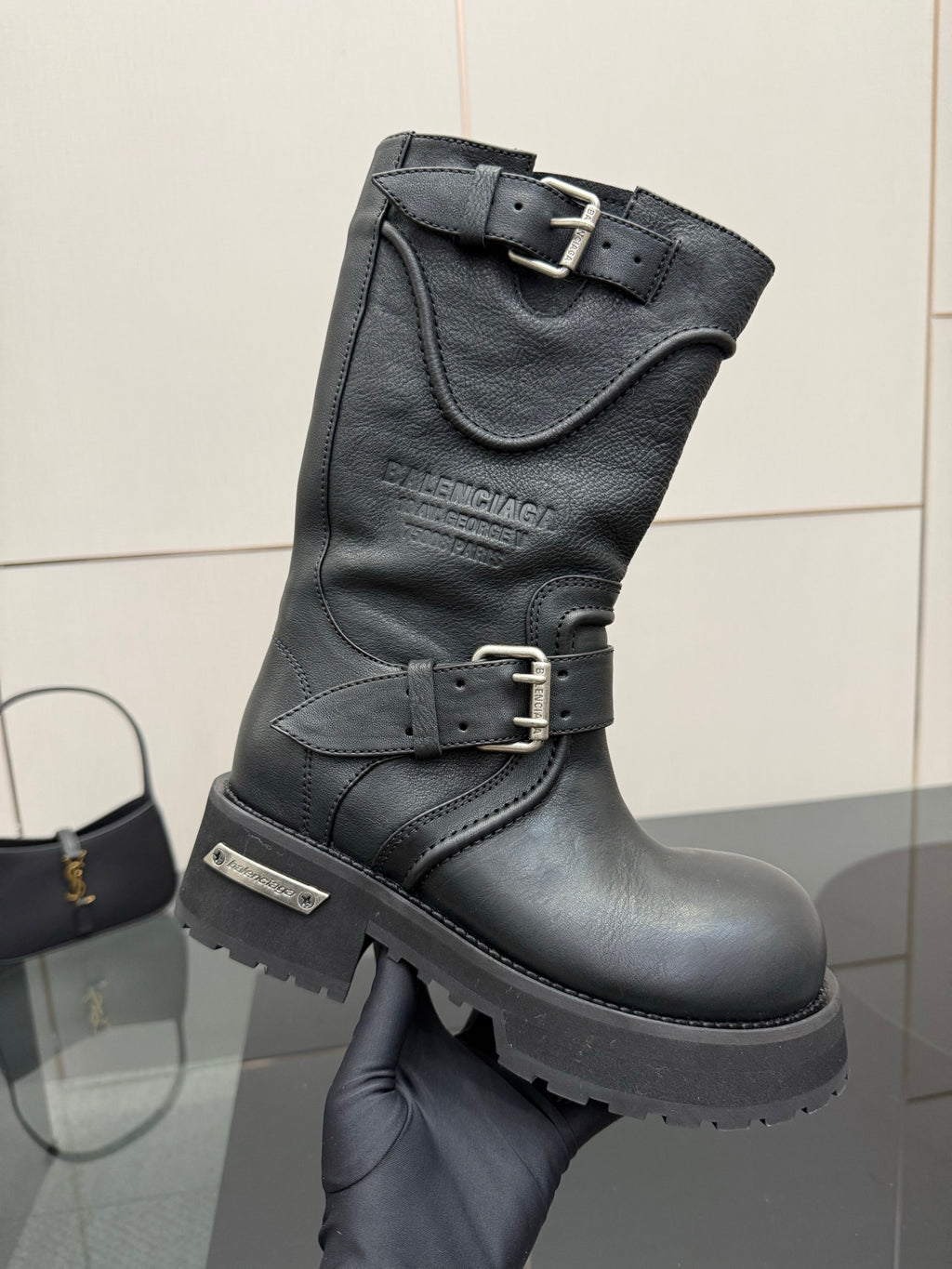Black leather knee-high boots with strap buckles and thick lug sole