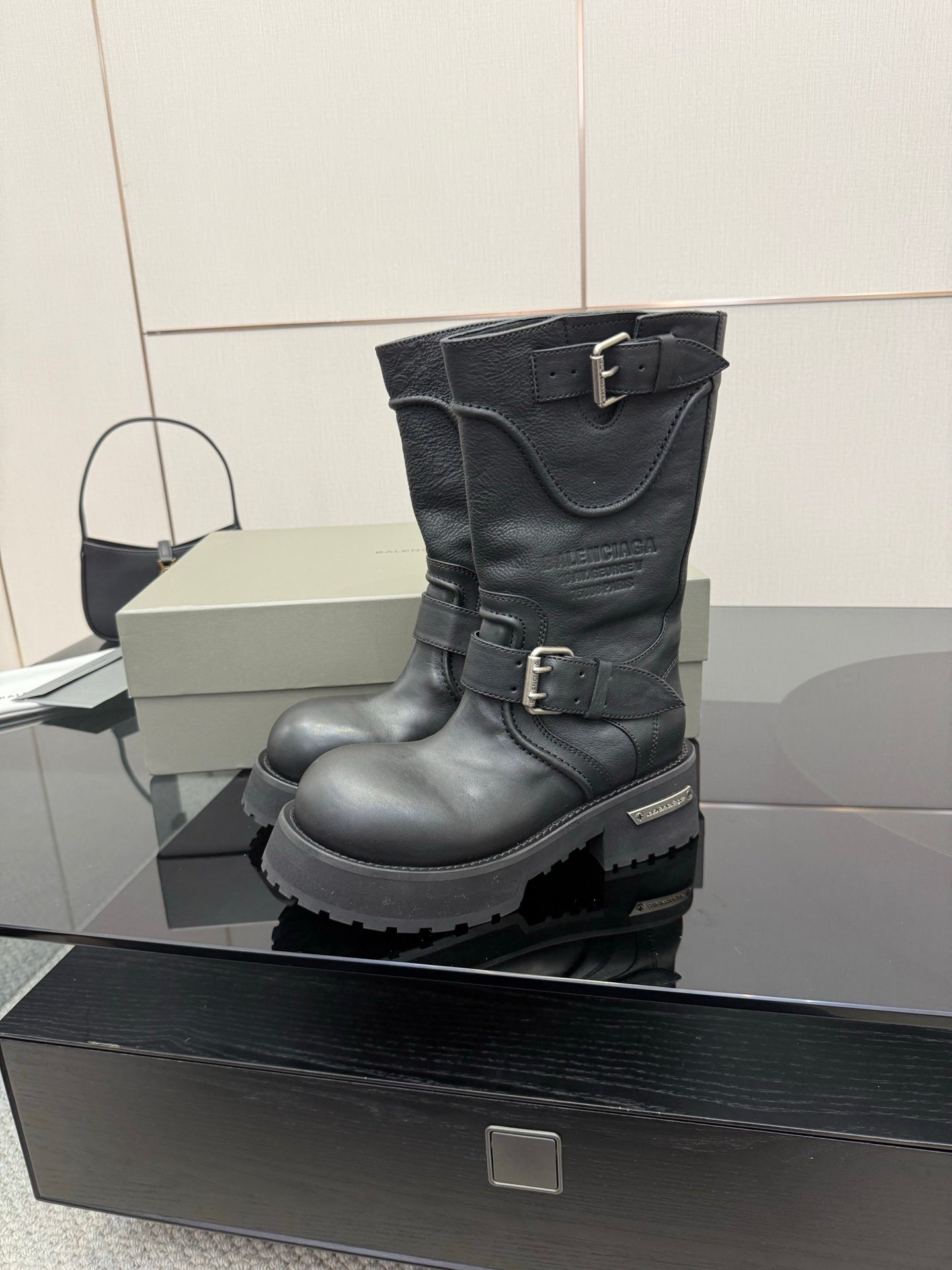 Black leather knee-high boots with strap buckles and lug sole