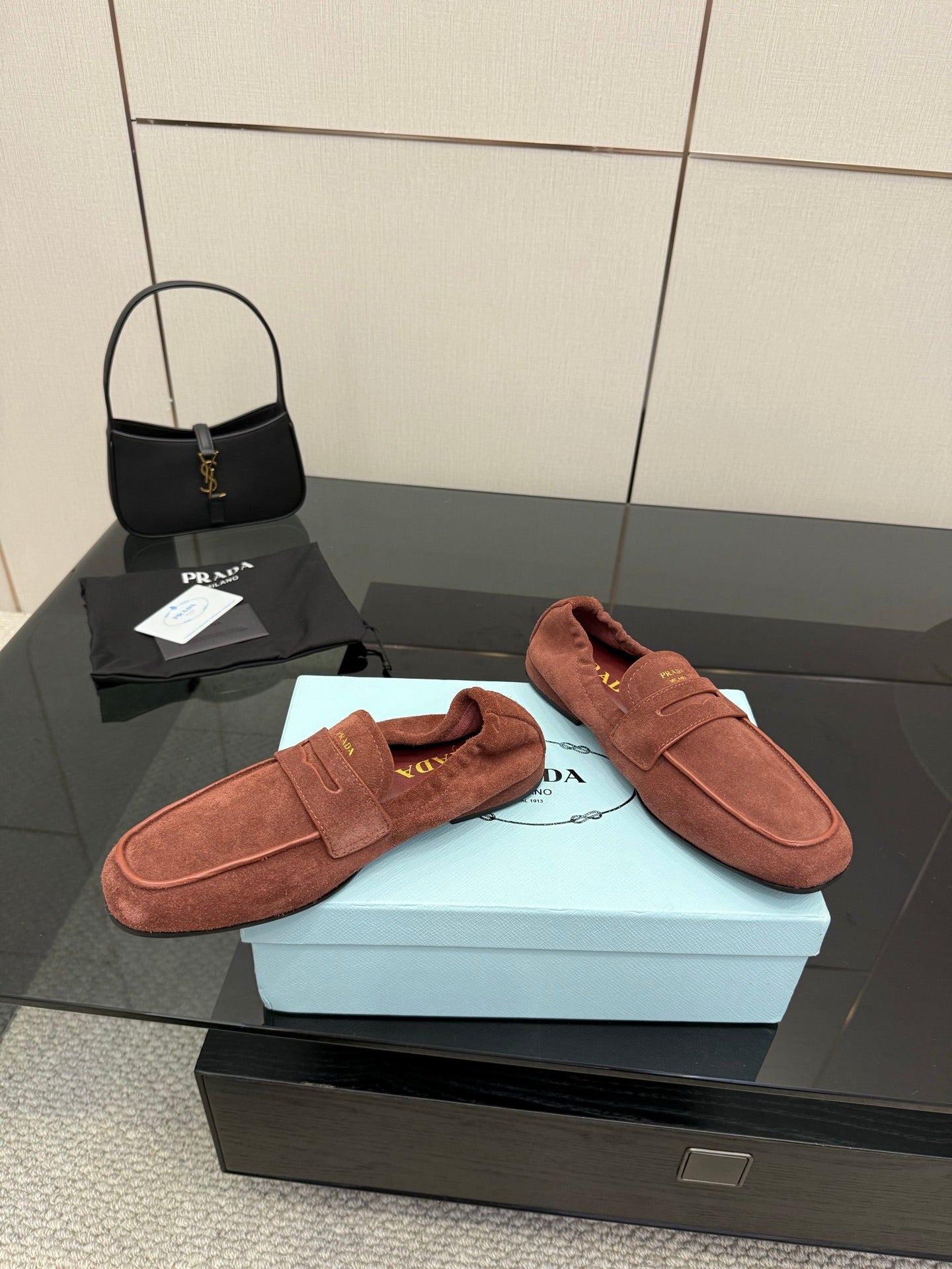 Prada rust-brown suede loafers with single strap and moc-toe stitching