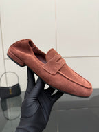 Prada rust-brown suede loafer held in hand, showing strap and upper