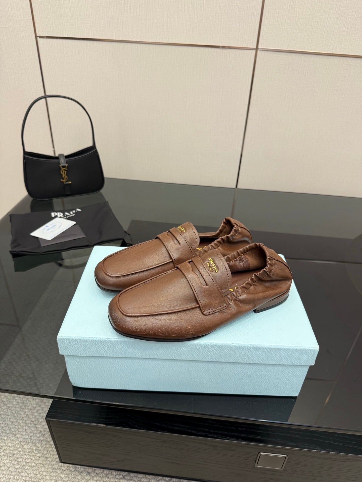 Brown leather loafers with strap over vamp and stitched upper detail, slip-on style