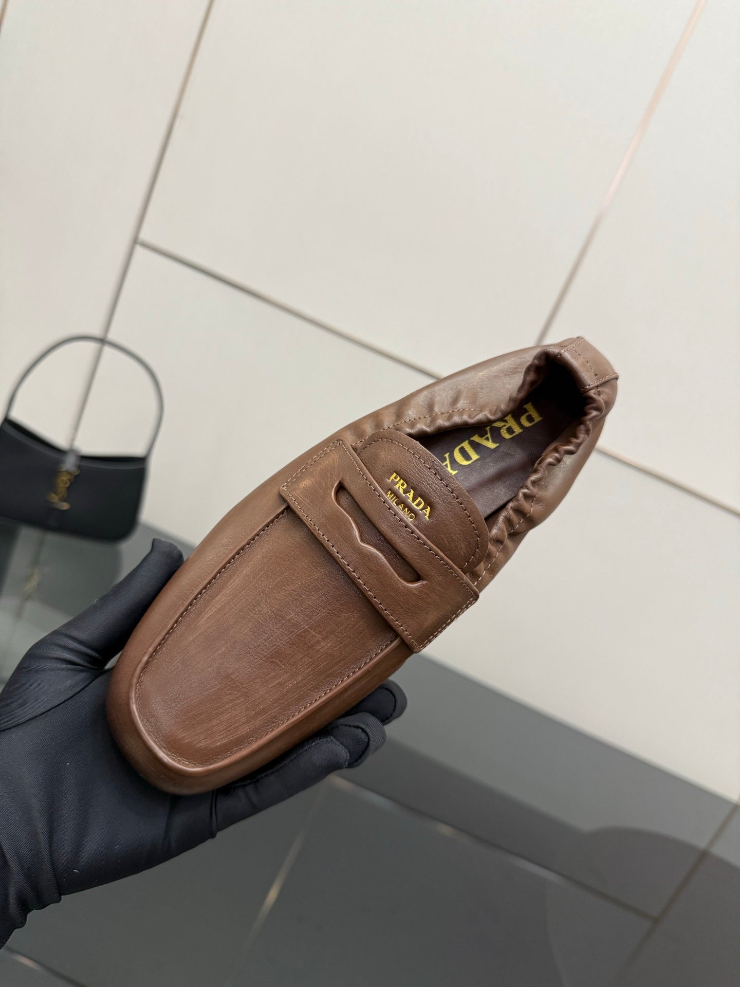 Tan leather loafer with Prada logo patch on strap, side view close-up