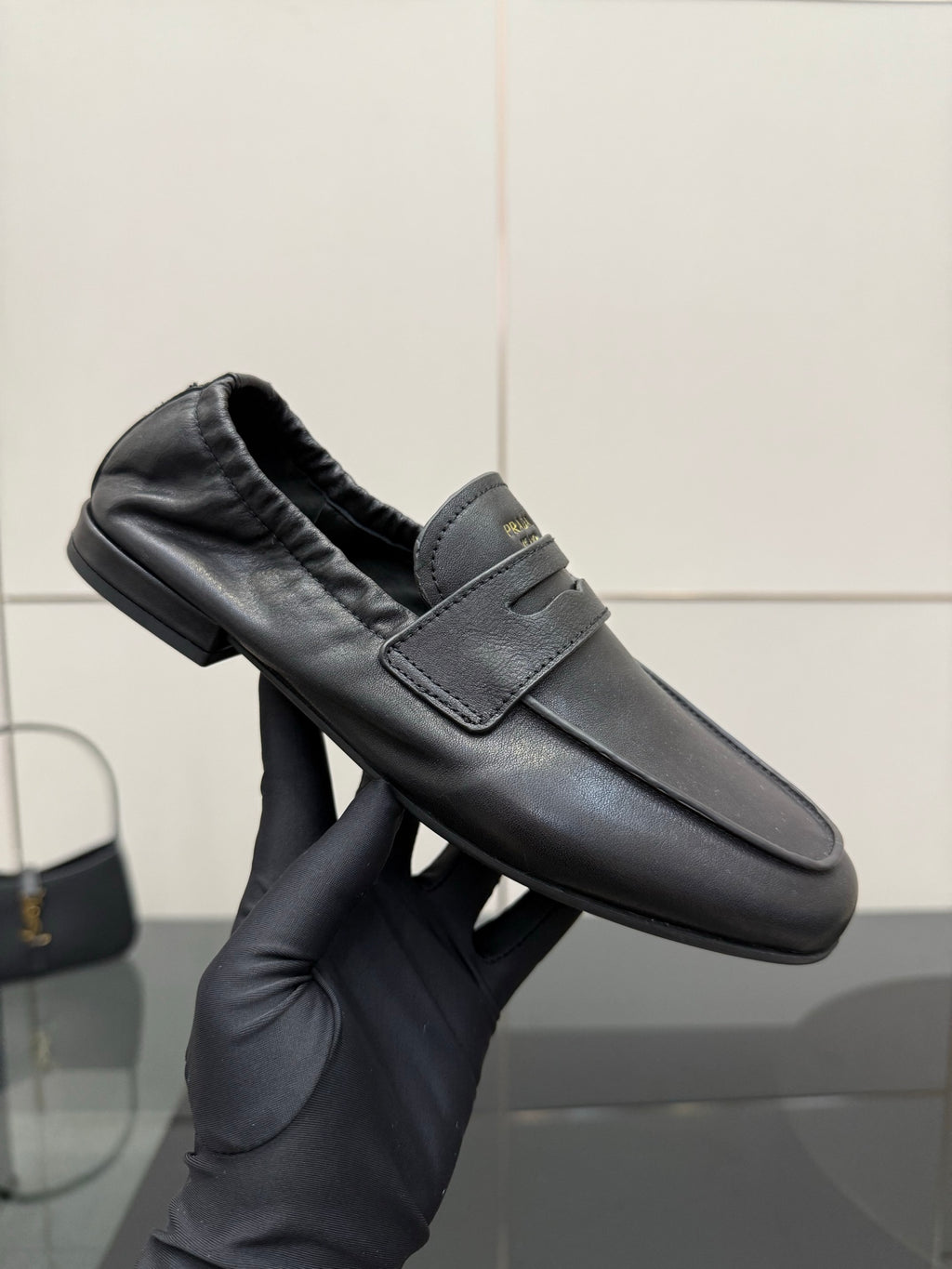 Black leather loafer in hand showing front strap, cushioned lining, low block heel