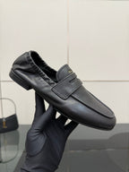 Black leather loafer in hand showing front strap, cushioned lining, low block heel