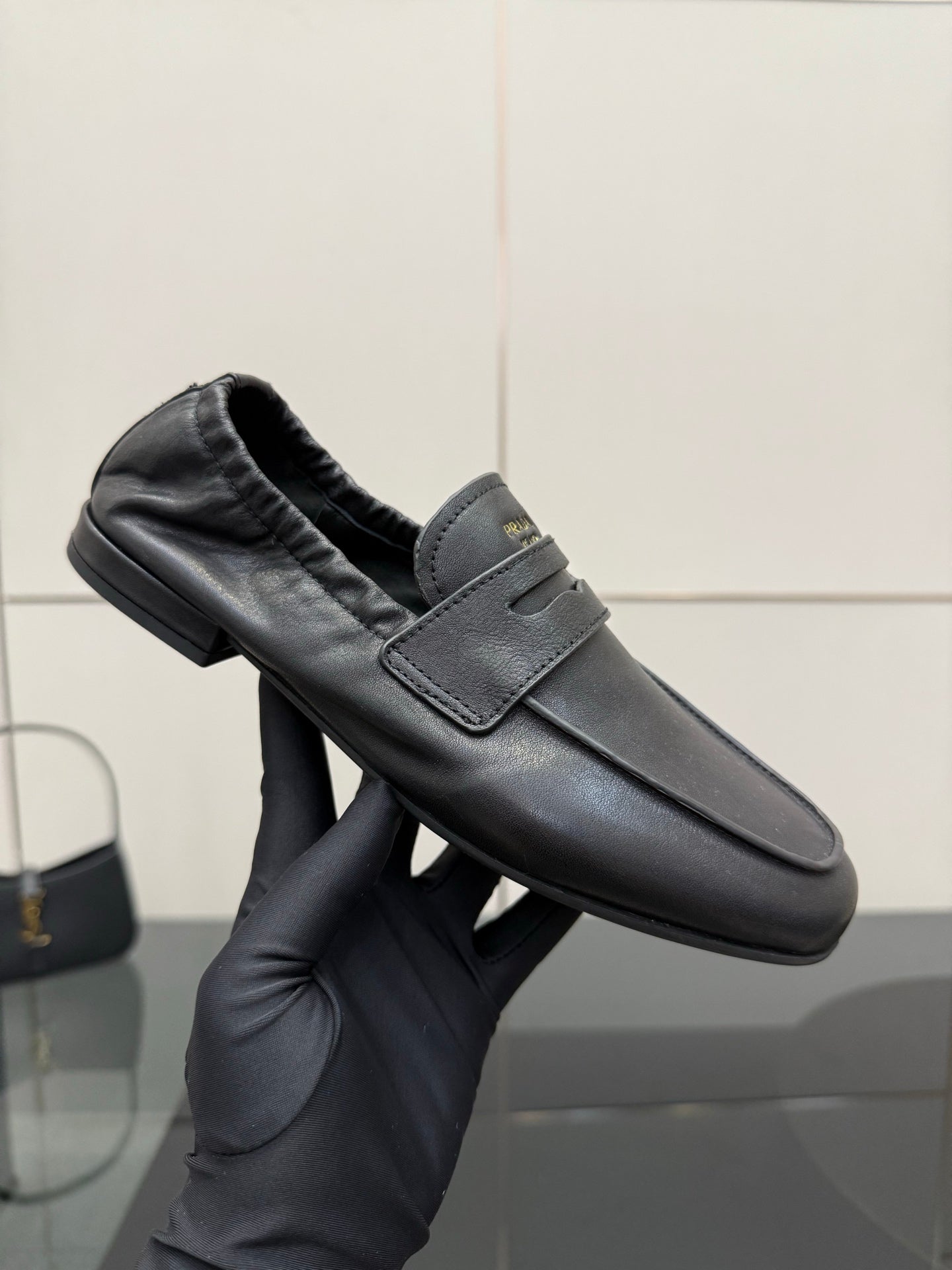 Black leather loafer in hand showing front strap, cushioned lining, low block heel