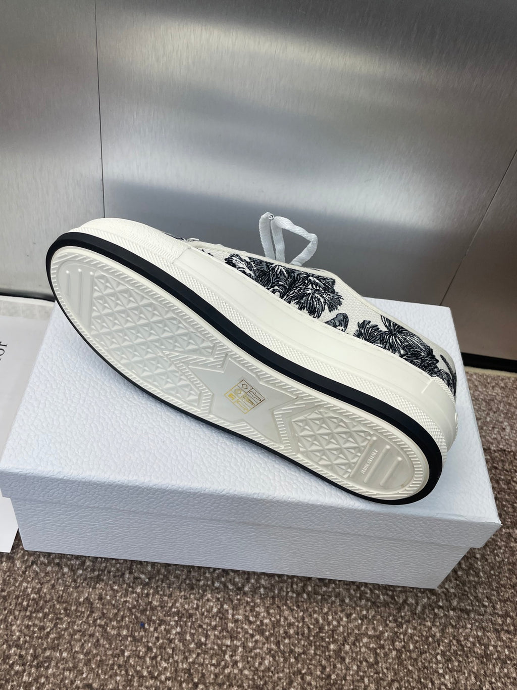 Unisex Dior sneakers, view of textured white outsole beneath black palm-print upper