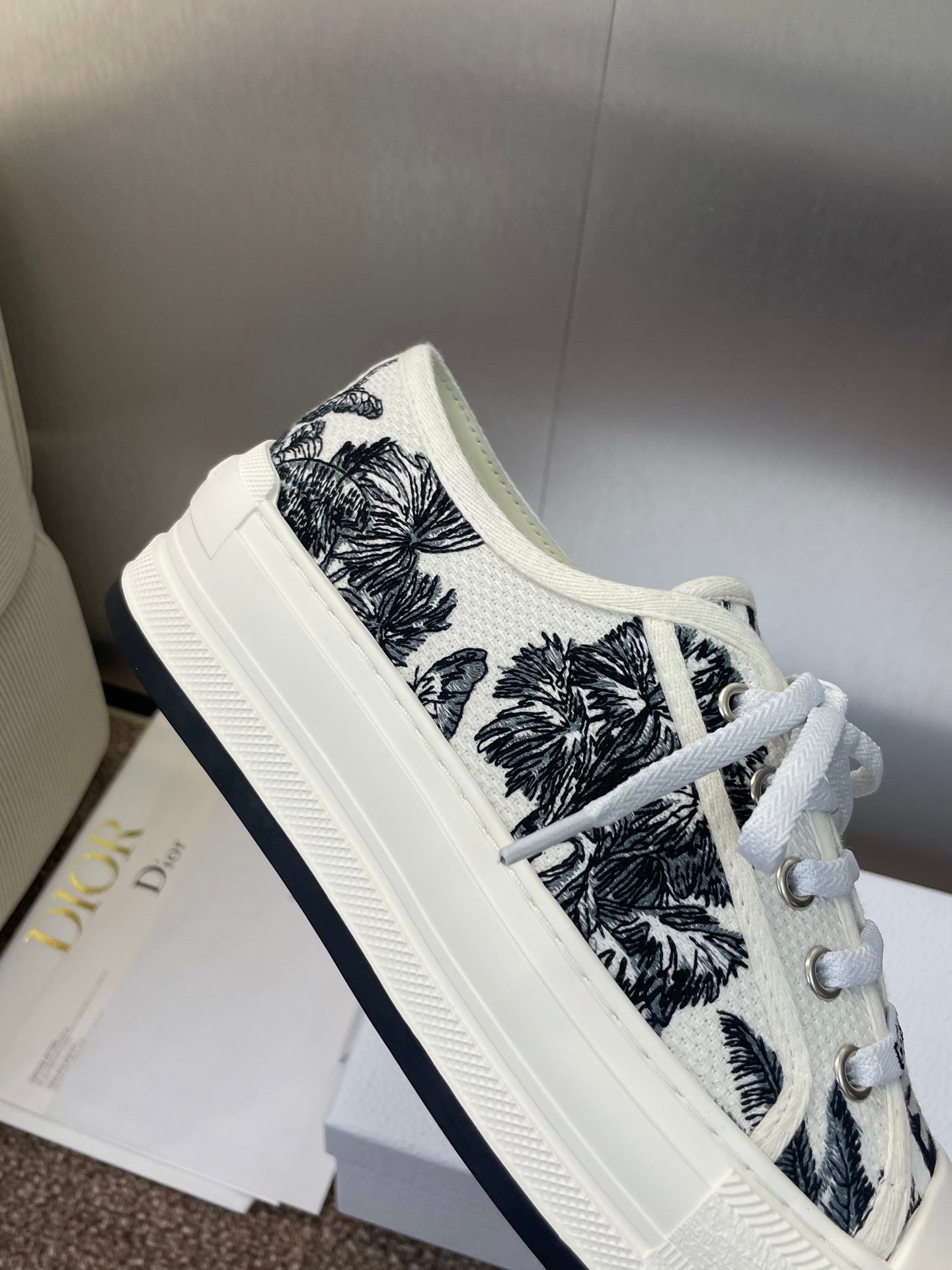 Unisex Dior sneakers close-up, white with black palm pattern, lace-up and thick sole