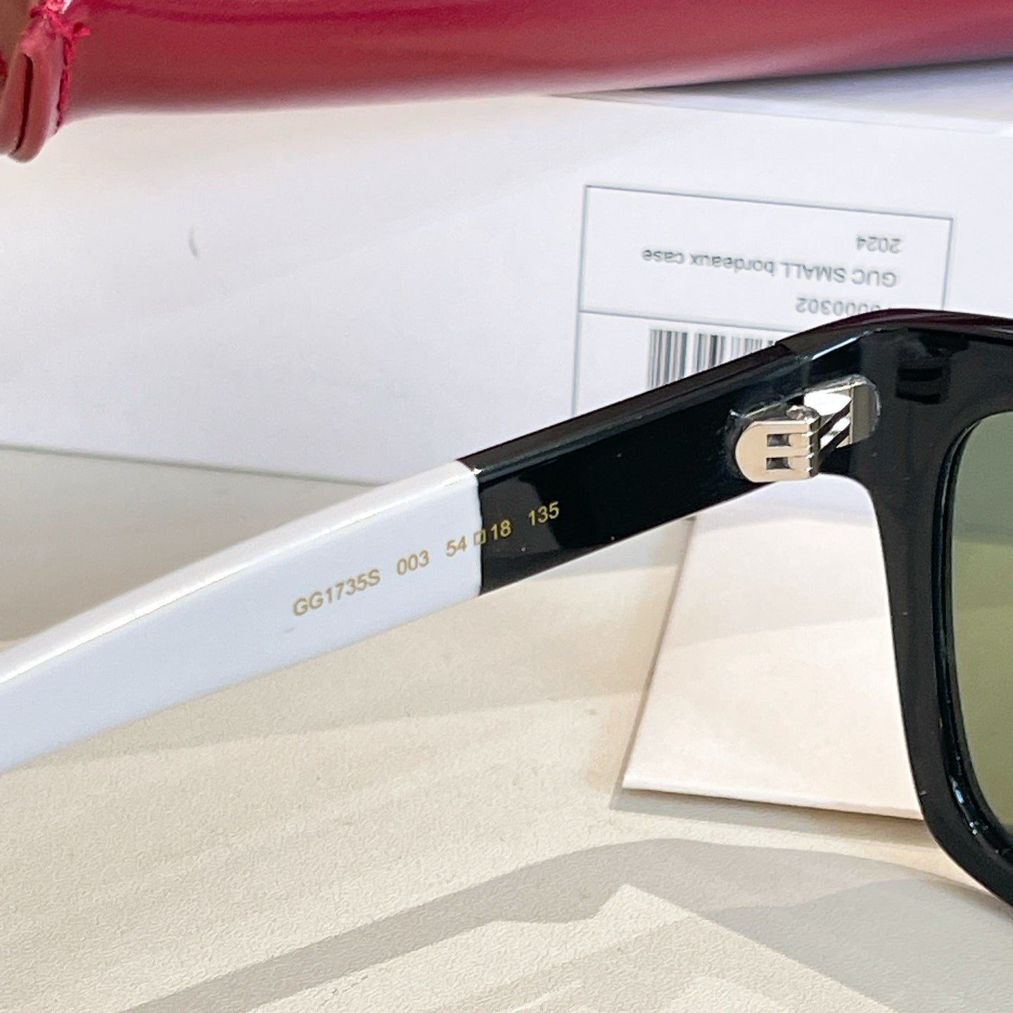 Black sunglasses temple with engraved numbers and gold-tone logo detail.
