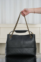 Chanel quilted black bucket bag with gold chain handles and top opening