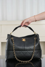 Chanel quilted black bucket bag with curved top handle and gold chain strap