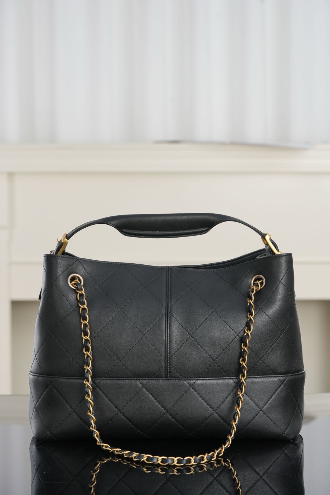 Chanel quilted black bucket bag with top handle and gold chain shoulder strap