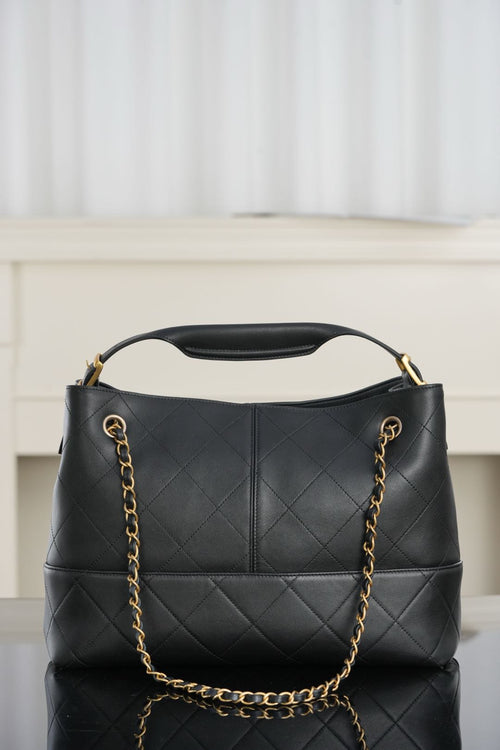 Chanel quilted black bucket bag with top handle and gold chain shoulder strap