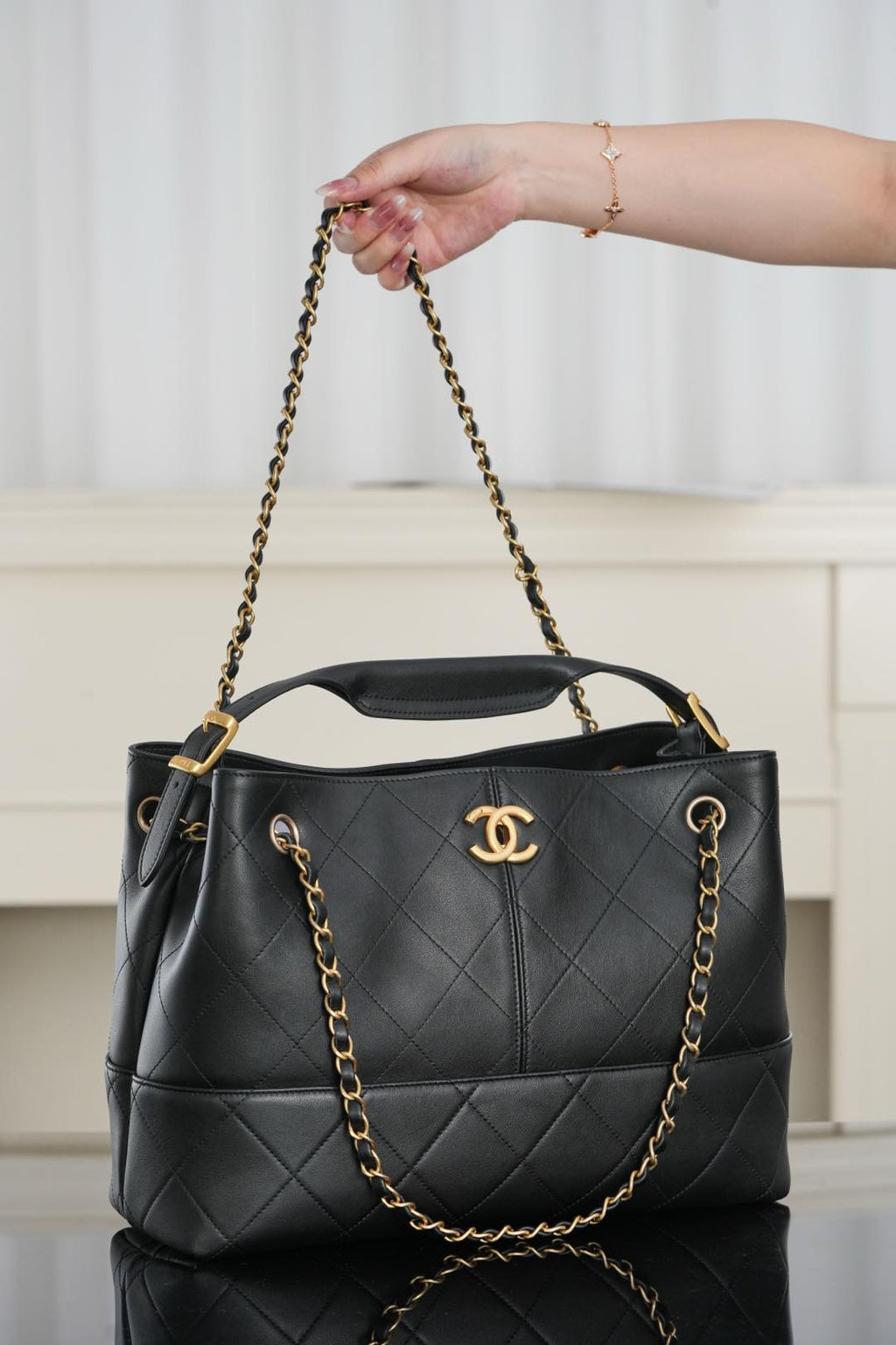 Chanel quilted black bucket bag held by gold chain handles