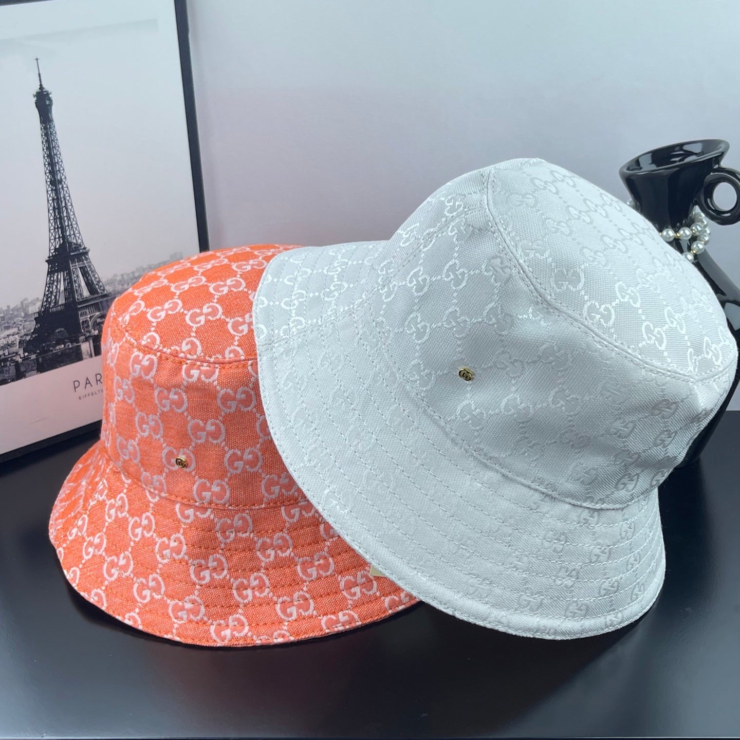 Orange and light-blue GG-print bucket hats with curved brims, pair