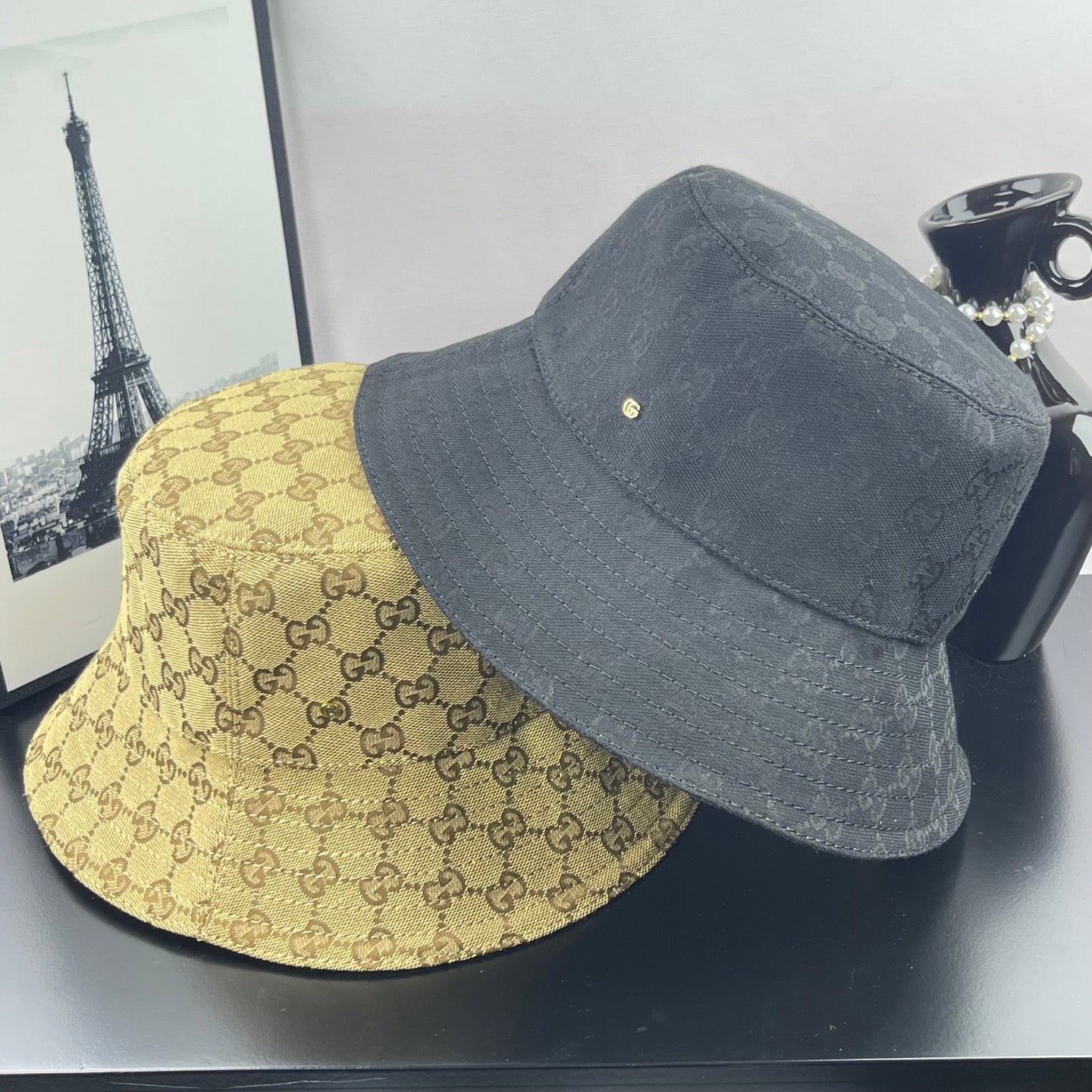Two bucket hats: dark gray and tan GG monogram, each with gold logo detail