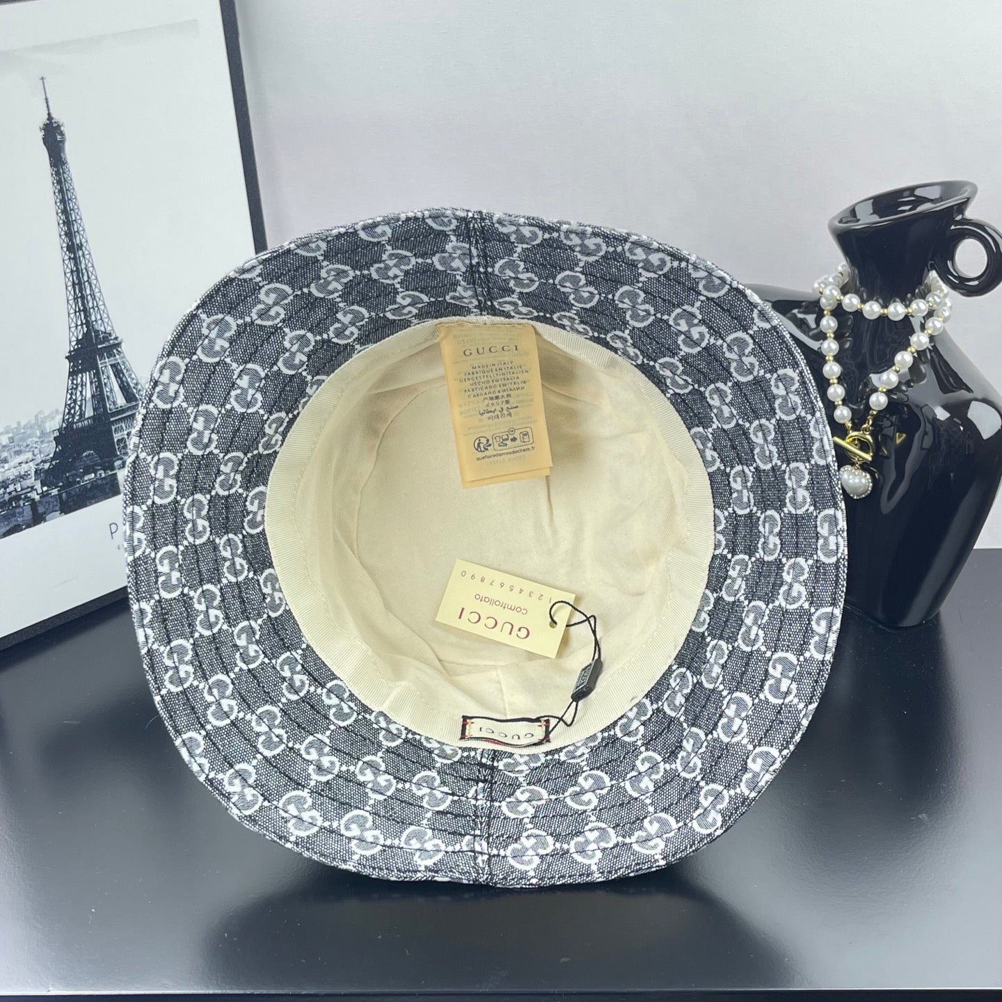 Gucci GG-print bucket hat, dark gray, underside view with cream lining and tags
