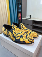 Pair of floral slip-on loafers, dark base with yellow ornate prints.