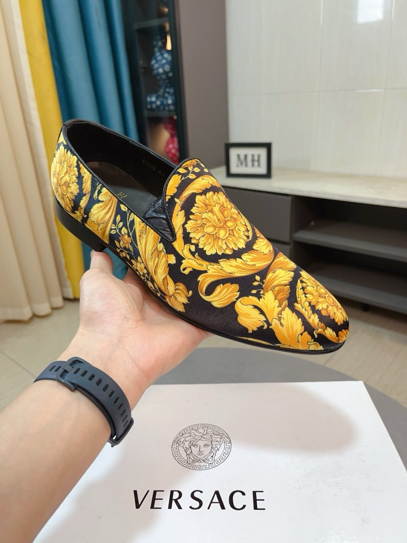 Floral slip-on loafer with dark upper, gold/yellow blossoms, and black cushioned heel.