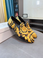 Side view of floral slip-on loafers, dark upper with vivid yellow baroque motifs.