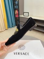 Black velvet loafer with gold Medusa emblem, held up for view