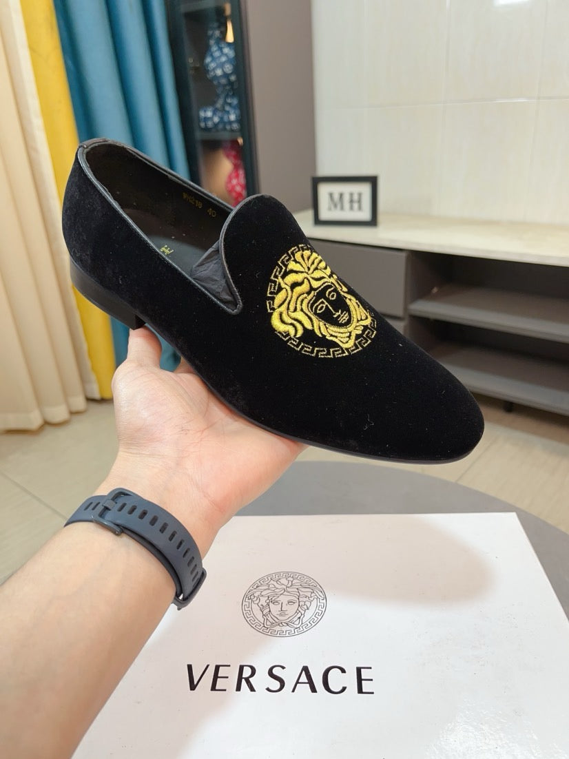 Black velvet loafer with gold Medusa logo, shown in hand