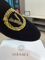 Close-up of black velvet loafer with gold embroidered Versace emblem
