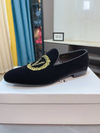 Black velvet slip-on loafers with gold embroidered emblem and low heel