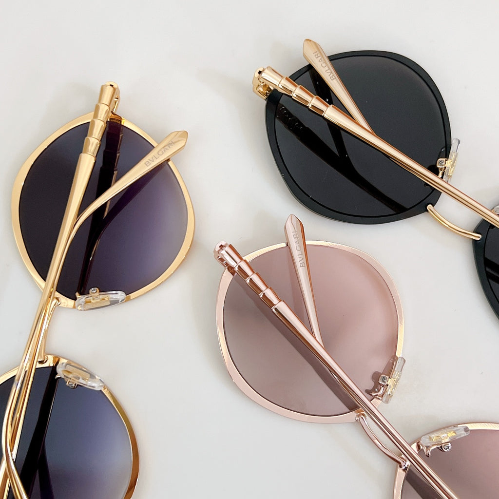 Multiple round sunglasses with gold-tone and pastel frames, mirrored lenses, on display.