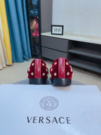 Rear view of red velvet loafers with gold studs and black heel panels.