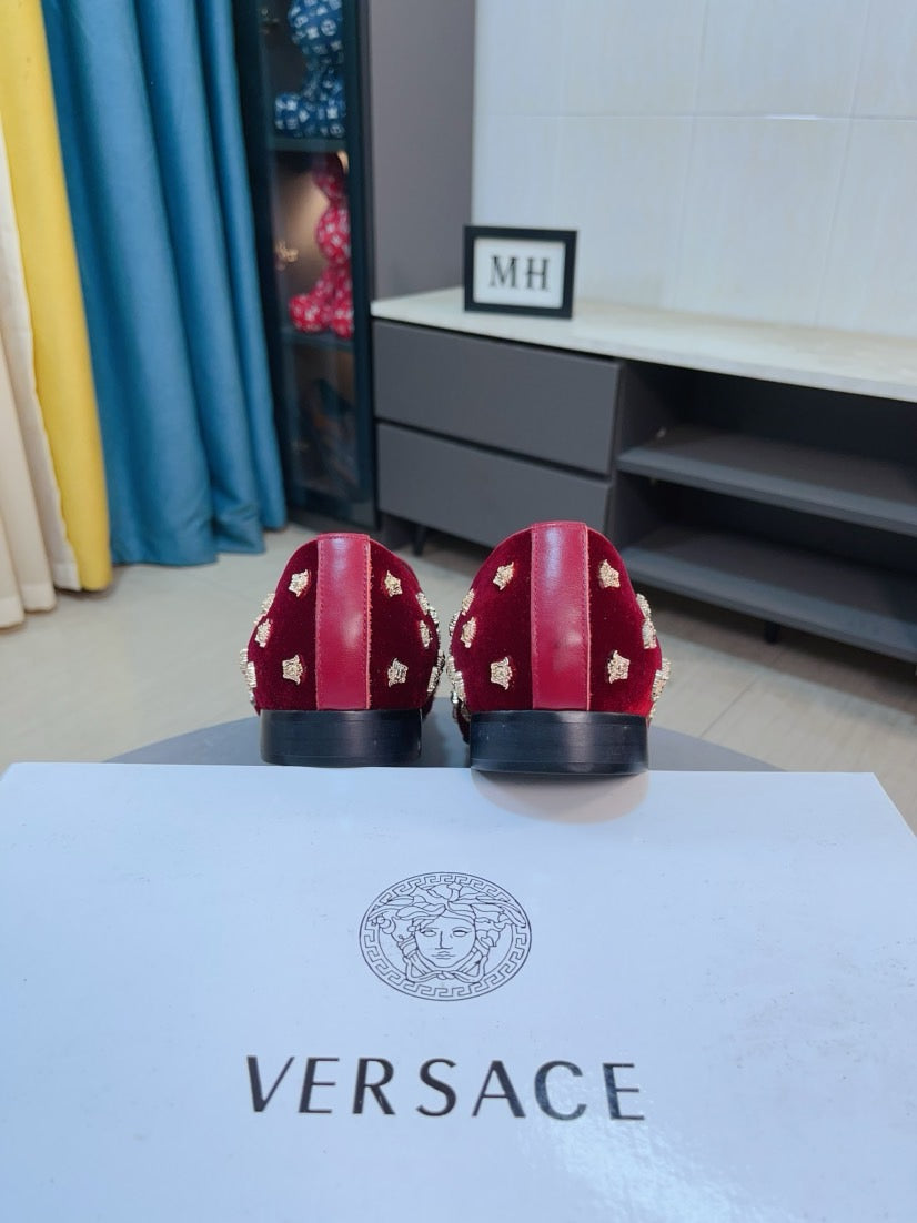 Rear view of red velvet loafers with gold studs and black heel panels.