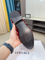 Back view of red velvet Versace loafers showing heel and dark interior lining.
