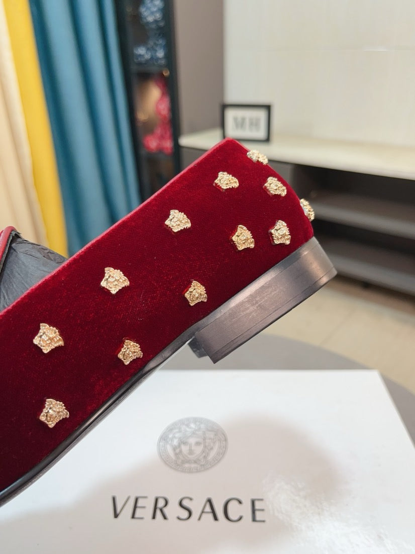 Side view of deep red velvet loafers with gold studs and block heel detail.