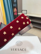 Side view of deep red velvet loafers with gold studs and block heel detail.