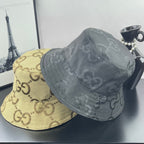 Gucci bucket hat pair: dark gray GG monogram hat with another yellow GG hat beside it