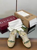 Pair of low-top sneakers with beige uppers, green graphic stripe, white laces
