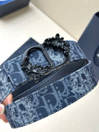 Blue monogram belt with black strap backing and detailed ornate buckle centerpiece.