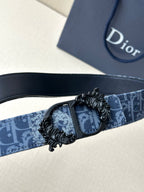 Blue monogram belt with black adjustable buckle and detailed medallion clasp.