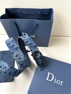 Dior belt with monogram strap and ornate black buckle with engraved edges.