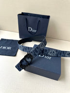 Navy Dior belt with monogram strap and ornate floral black buckle clasp.
