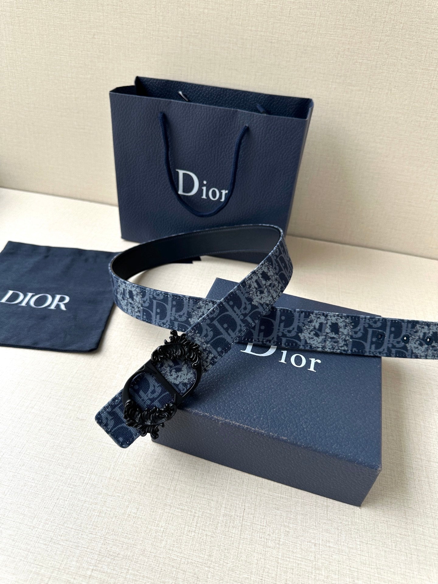Navy Dior belt with monogram strap and ornate floral black buckle clasp.